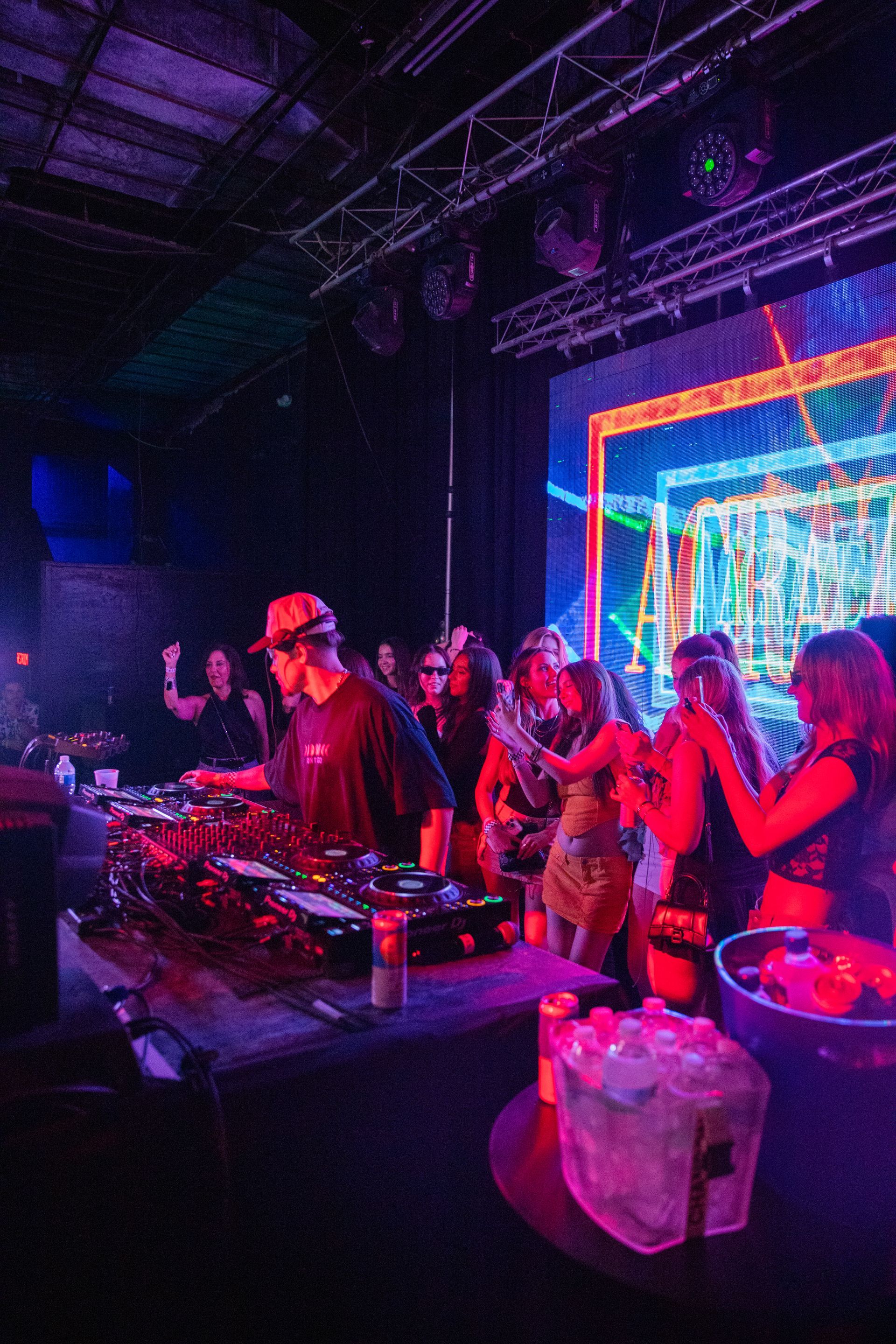 A group of people are standing in a dark room at a party.