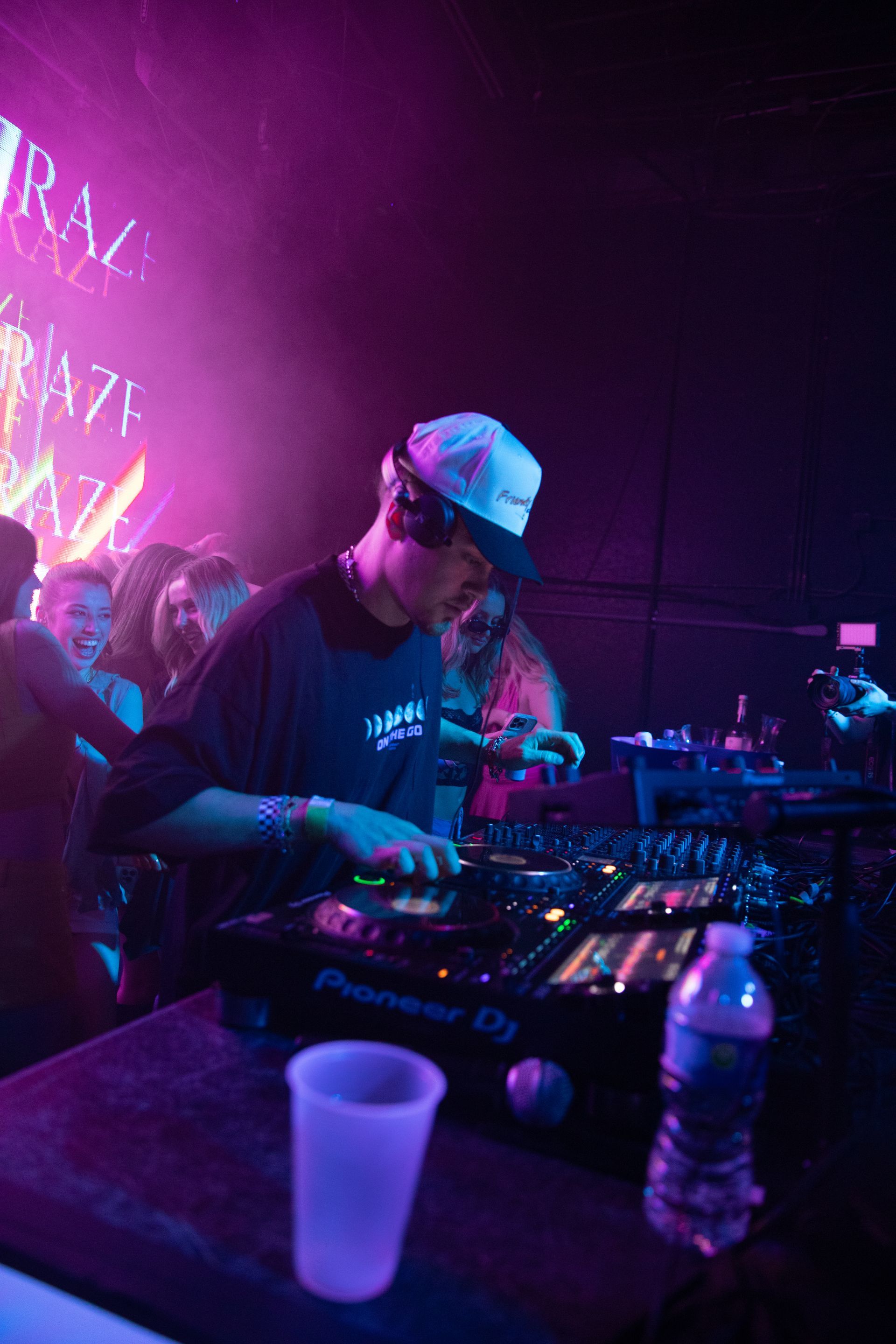 A dj is playing music at a party in a dark room.