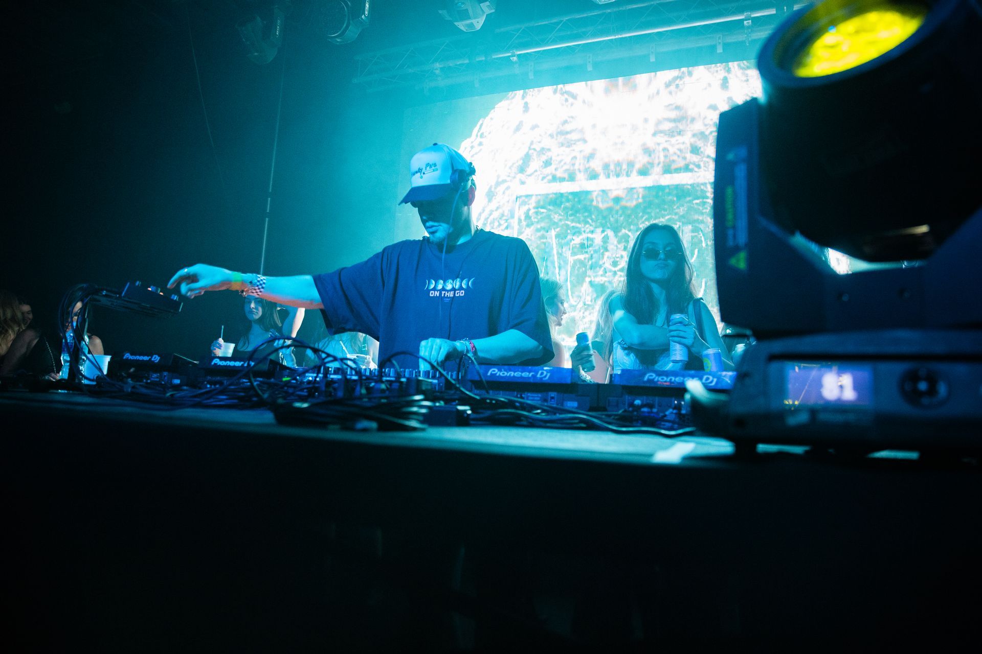 A man is playing a dj set in a dark room.