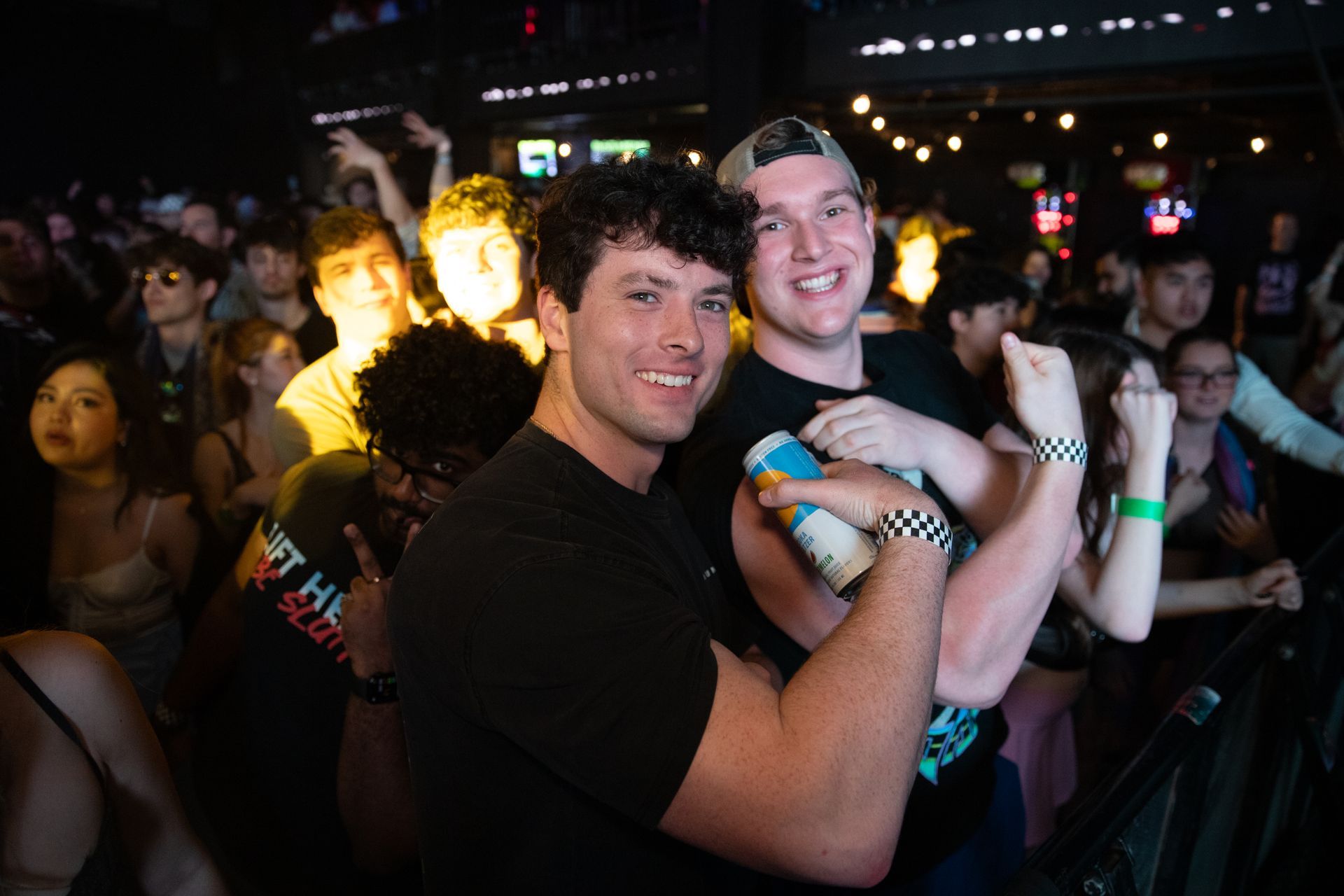 Two men are posing for a picture in front of a crowd at a concert.