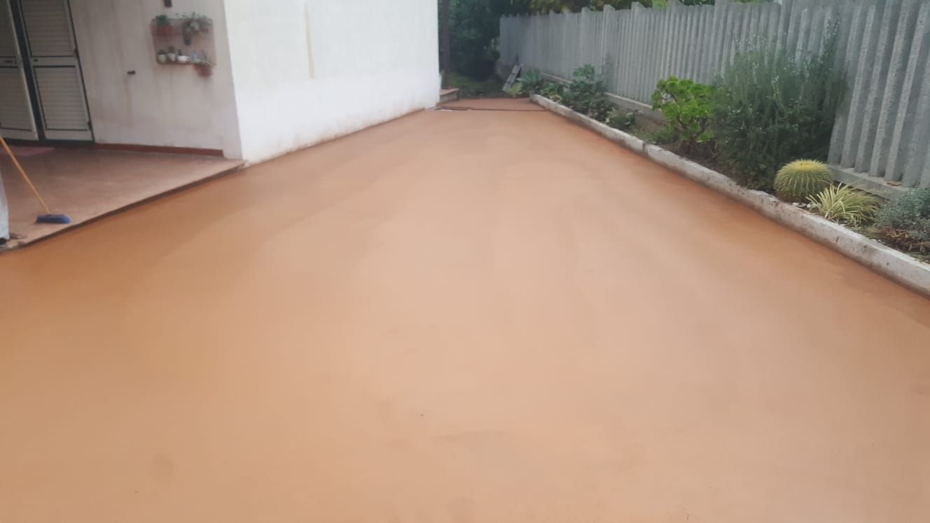 Un vialetto di cemento marrone con una recinzione bianca sullo sfondo.