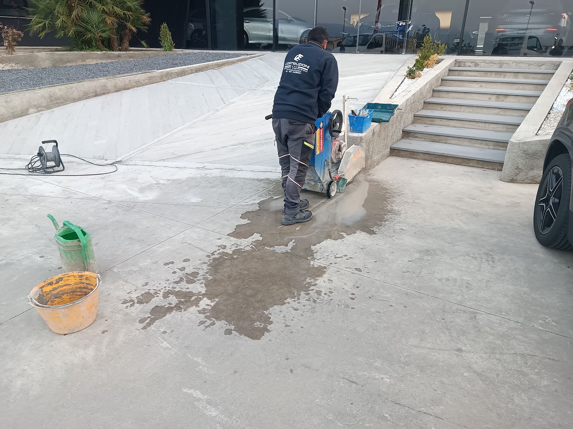 Un uomo sta usando una macchina per tagliare il cemento in un parcheggio