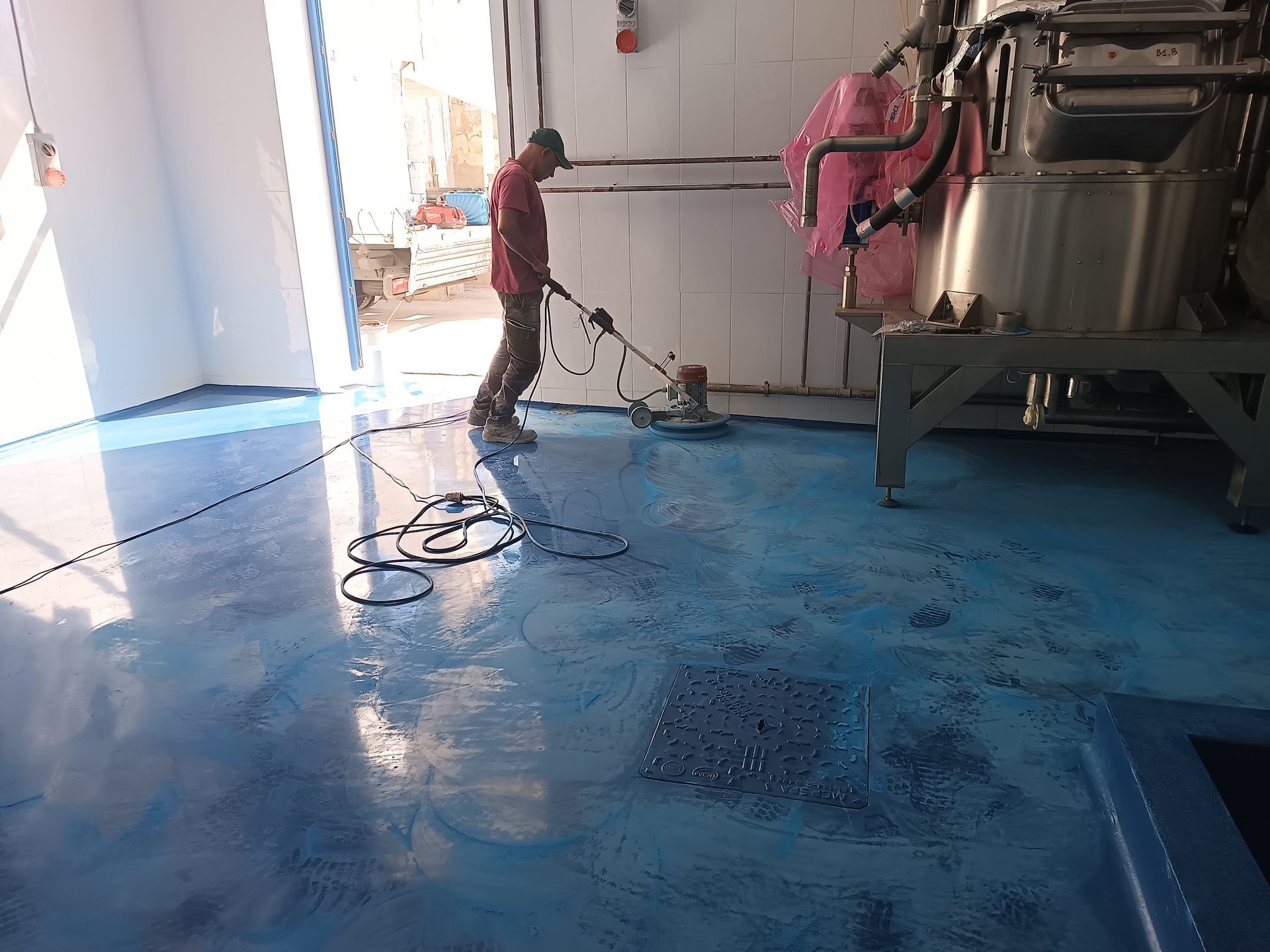 Un uomo sta pulendo un pavimento blu con un aspirapolvere