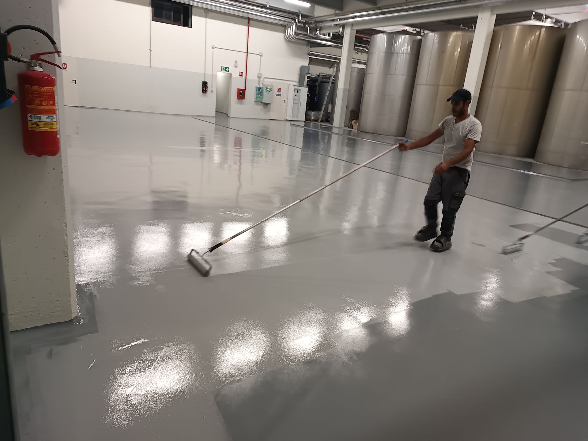 Un uomo sta dipingendo il pavimento di un edificio con un rullo