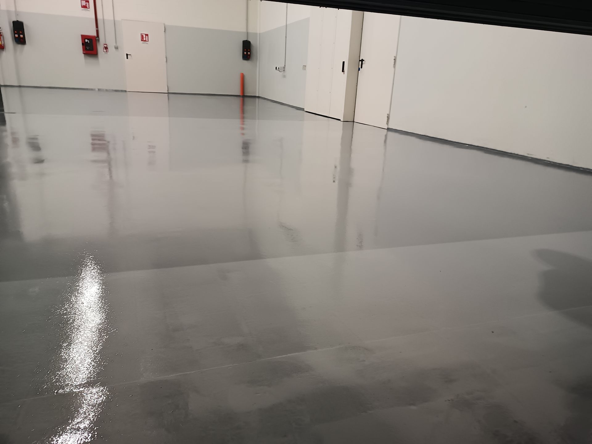 Una grande stanza con pavimento grigio e pareti bianche