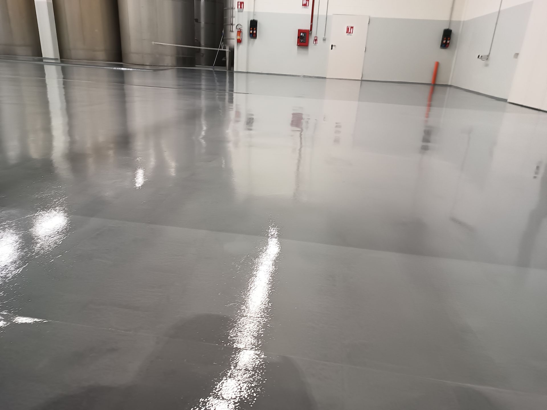 Un magazzino con un pavimento grigio e un estintore rosso sul muro