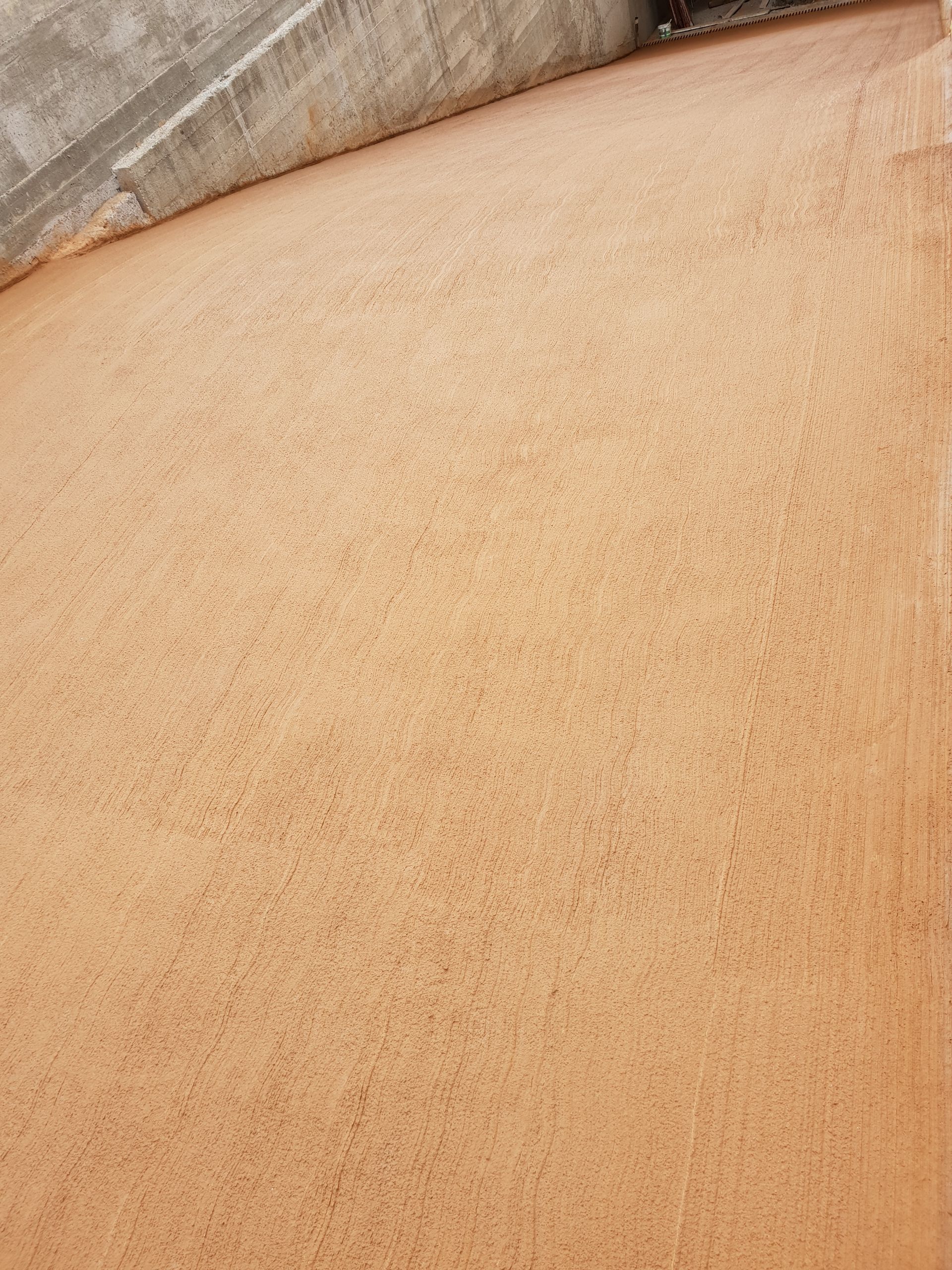 Un primo piano di una superficie sabbiosa con un muro di cemento sullo sfondo.