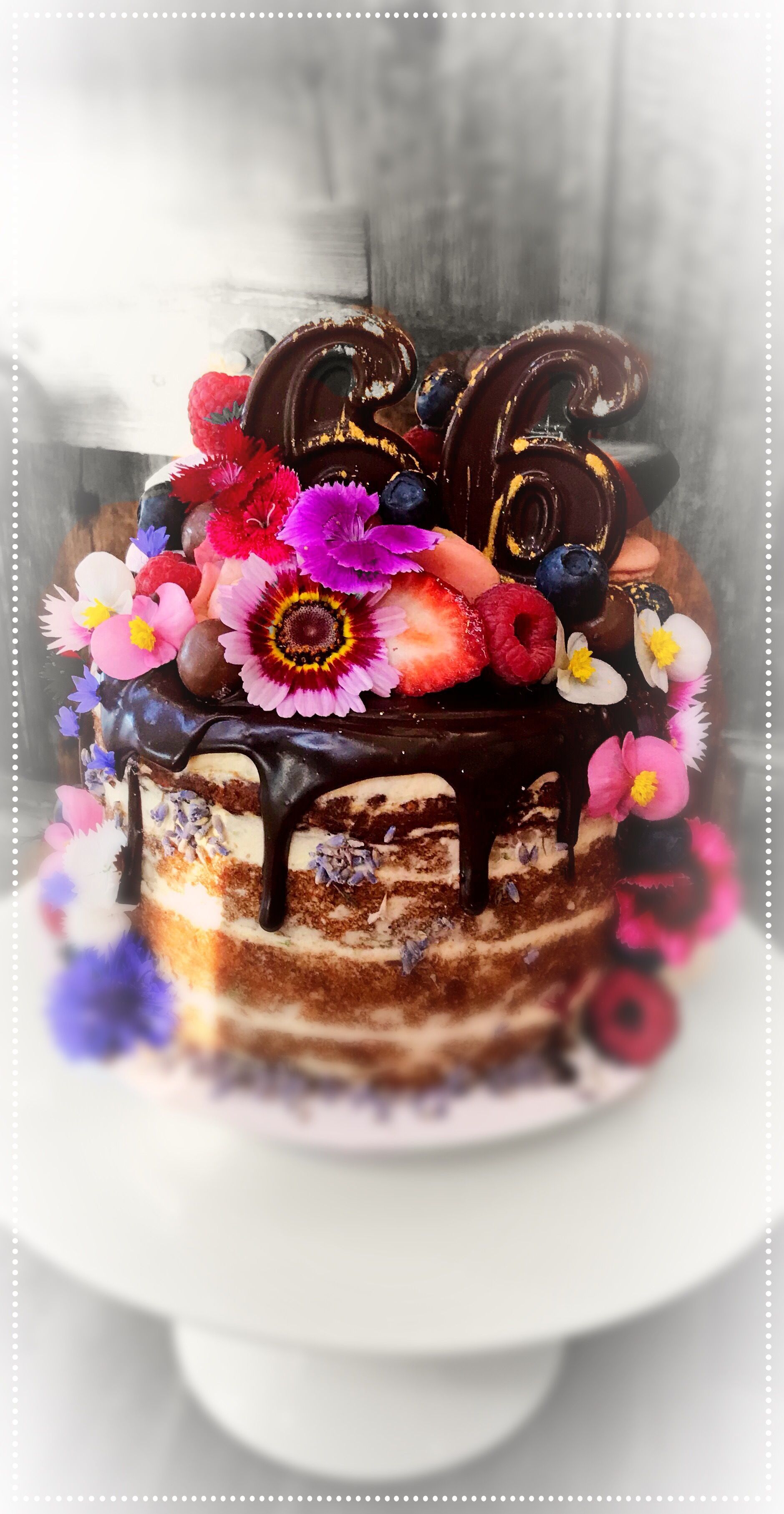 A cake with chocolate icing and flowers on top of it — My Rainbow Bakery, Cafe & Catering in Cannonvale, QLD