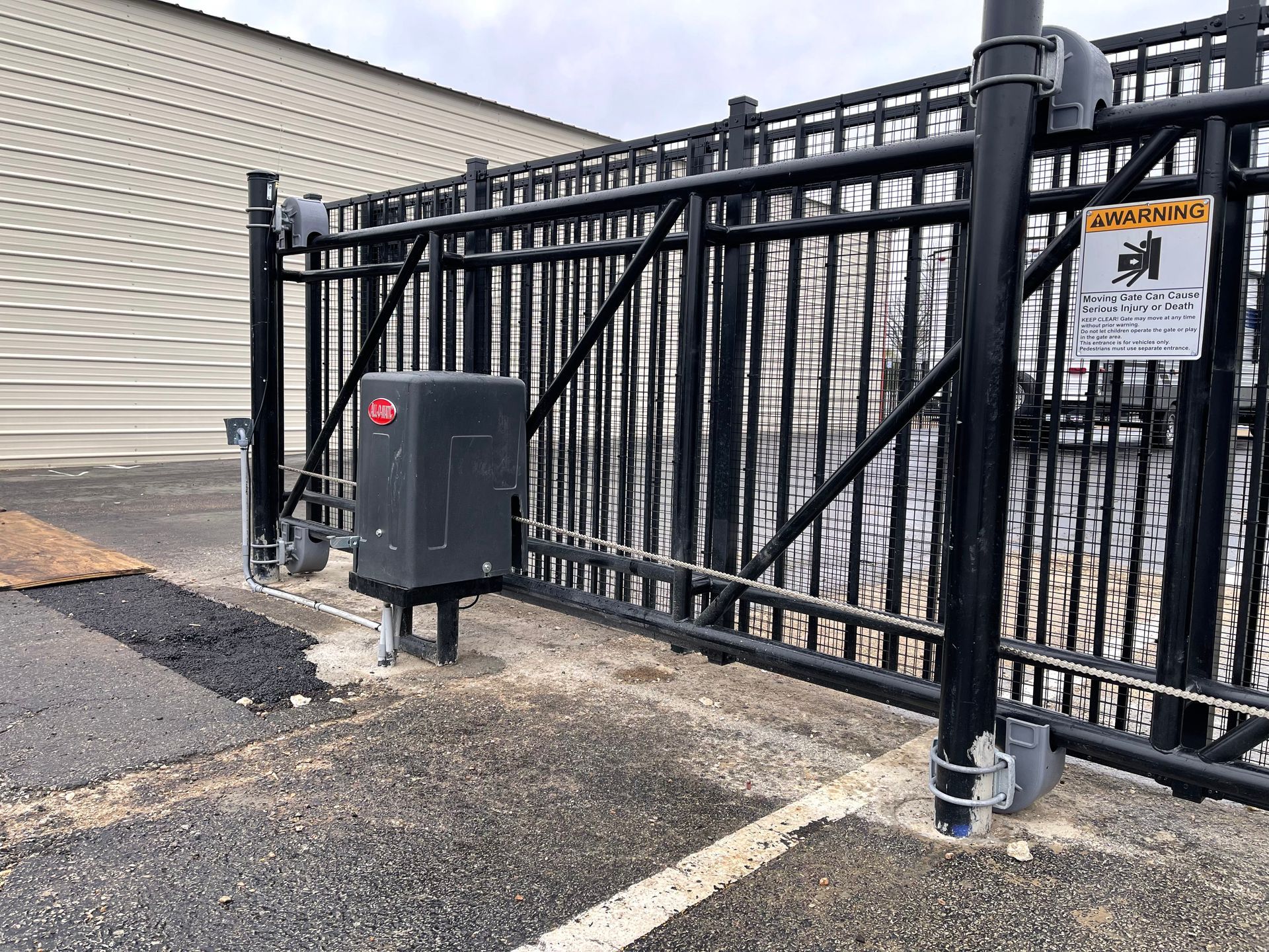 A sliding gate with a motor attached to it is sitting in front of a building.
