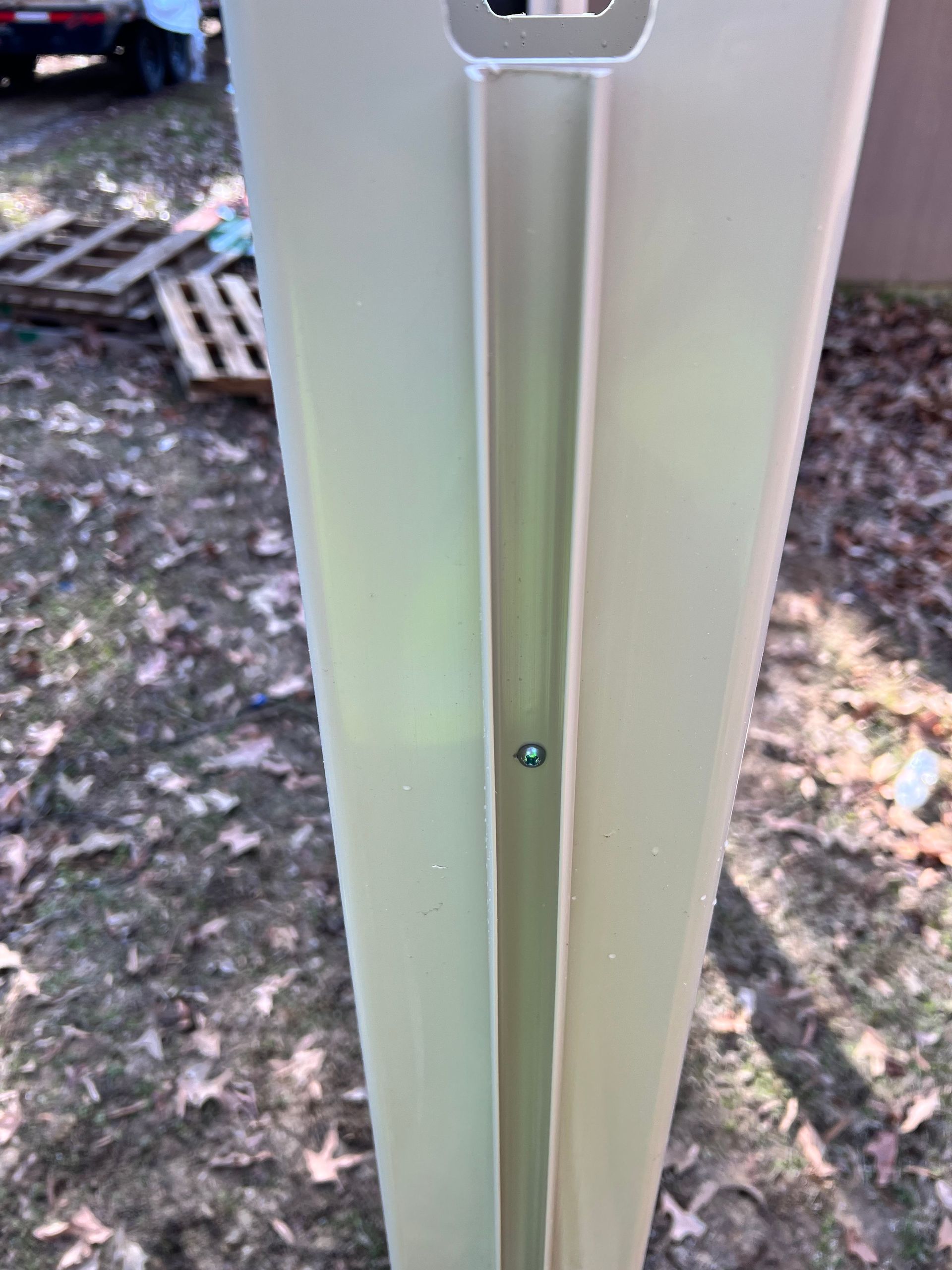 A close up of a white pole with a screw in it.