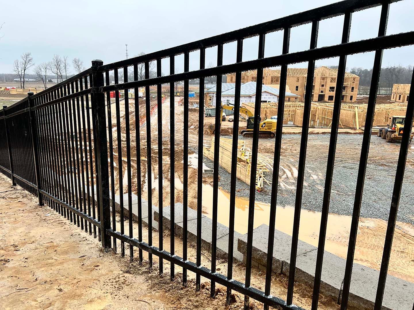 A black metal fence surrounds a construction site.
