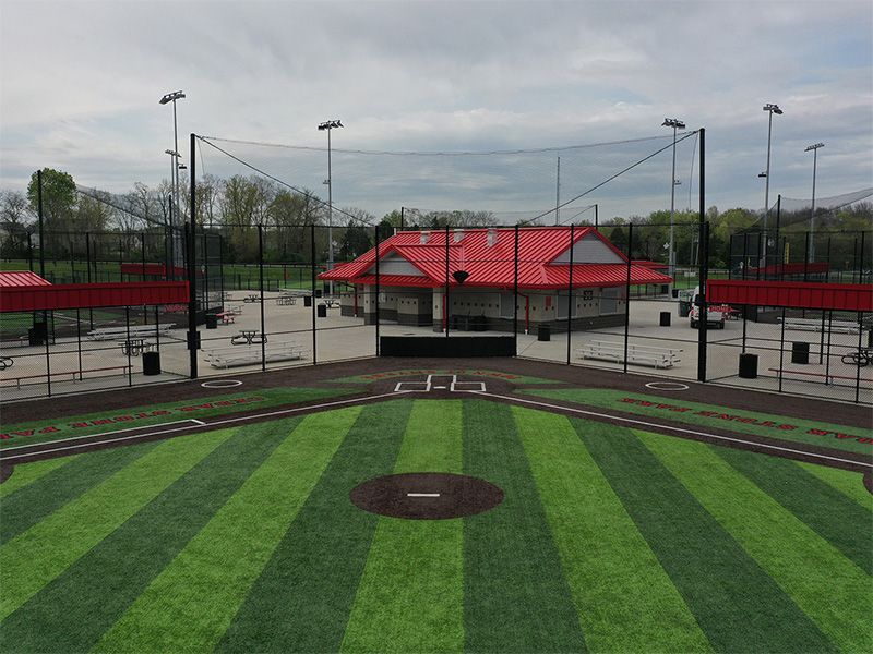 An aerial view of a baseball field with a red building in the background.