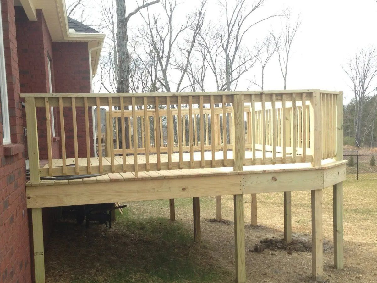 A wooden deck is being built in front of a brick house.