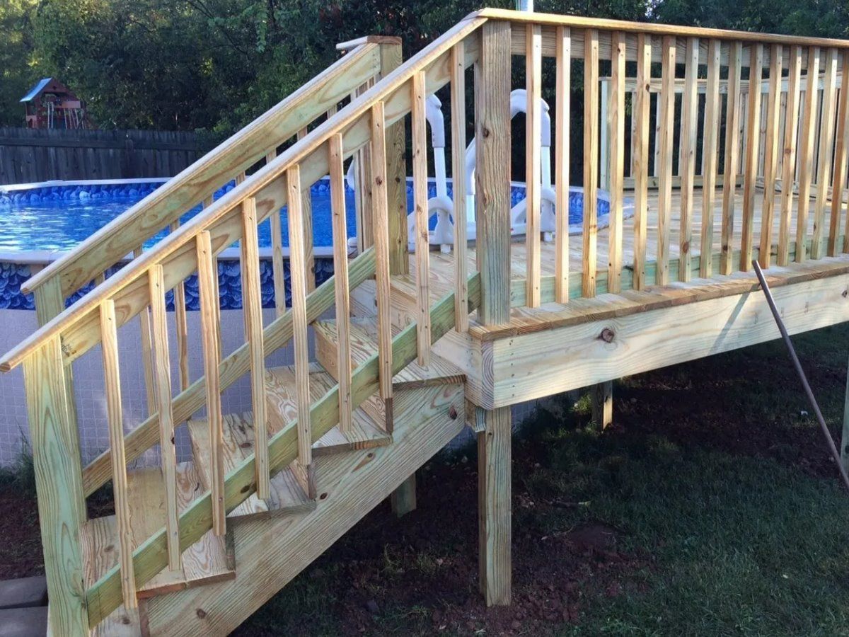 A wooden deck with stairs leading up to a pool