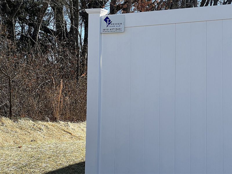 A white fence with a blue sticker on it is in the middle of a field.