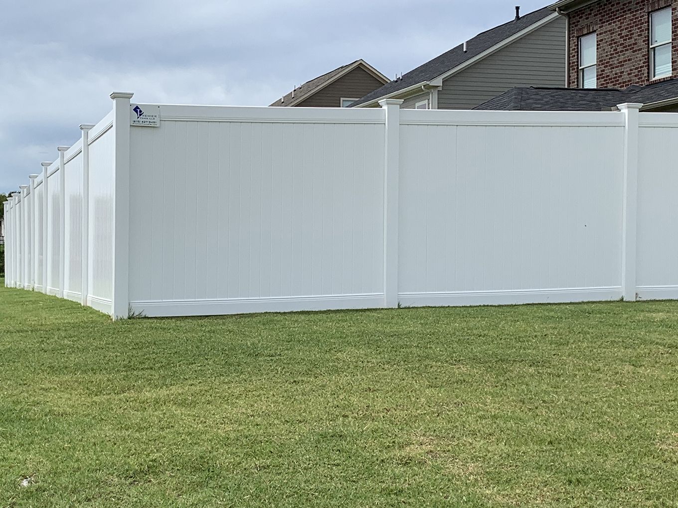 A white fence is in the backyard of a house.