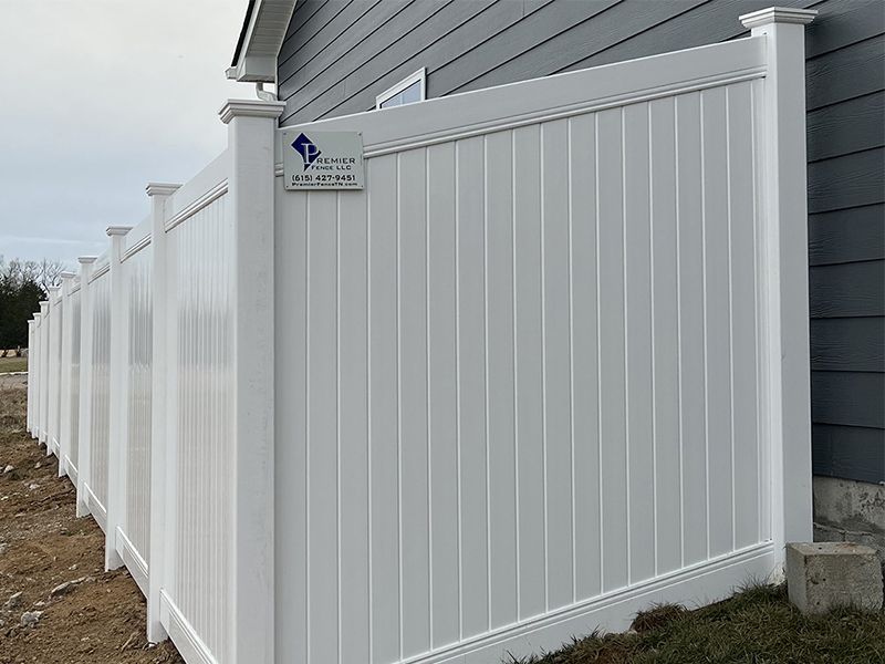 A white vinyl fence is sitting in front of a house.