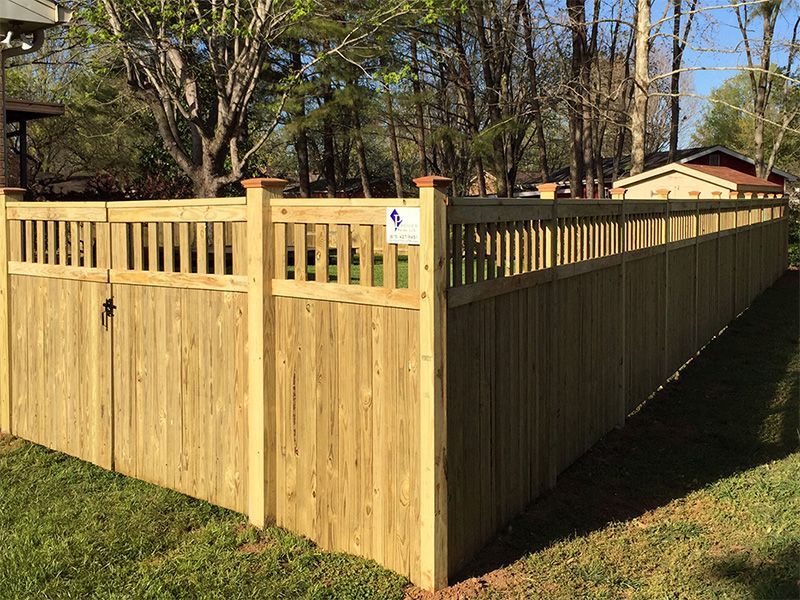 A wooden fence with a gate in the backyard of a house.