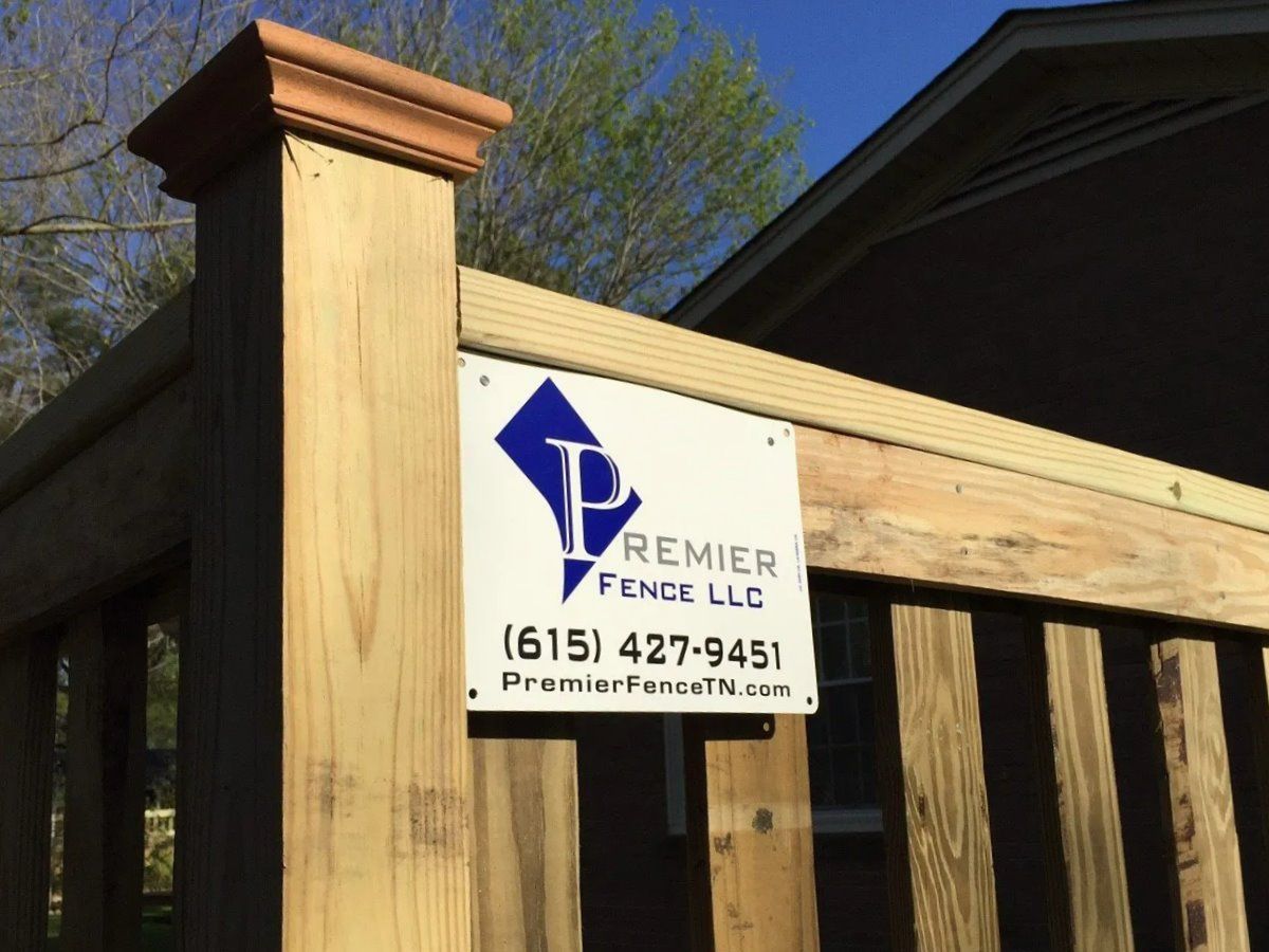 A wooden fence with a sign that says premier fence llc