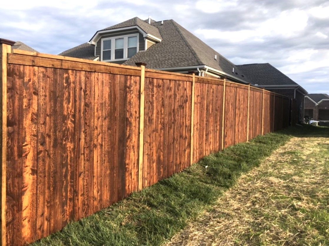 A wooden fence is sitting in the grass in front of a house.