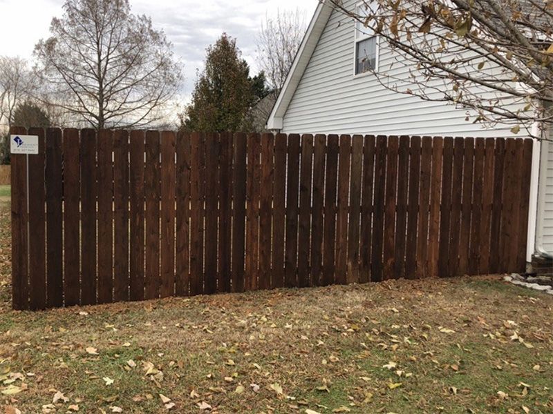 A wooden fence is in front of a white house.