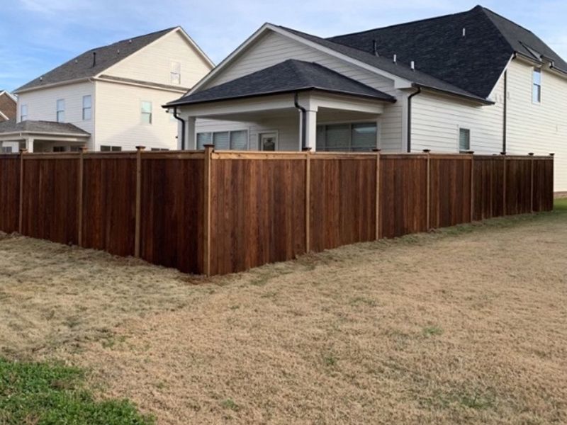 A wooden fence is in the backyard of a house.