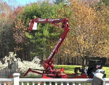 A red crane is sitting in a yard next to a white railing.