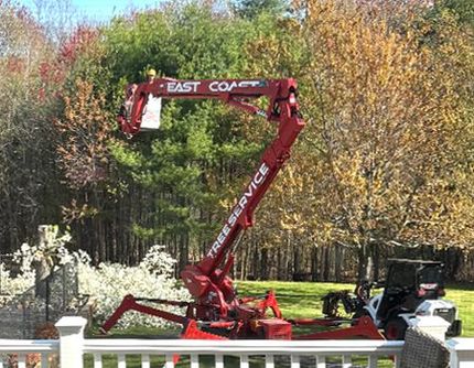 A red crane is sitting in a yard next to a white railing.