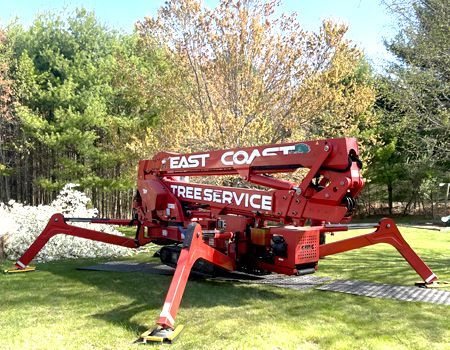 A red spider lift is parked in a grassy field.