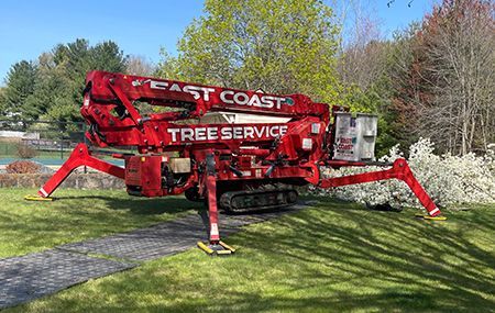 A red spider lift is parked in a grassy field.