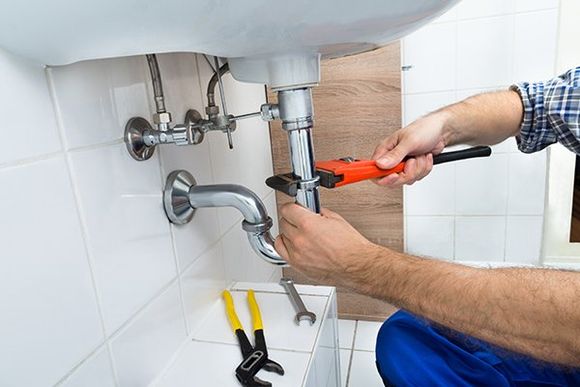 Plumber Fixing Sink in Bathroom — Garden City, MO — Mills Plumbing & Contracting