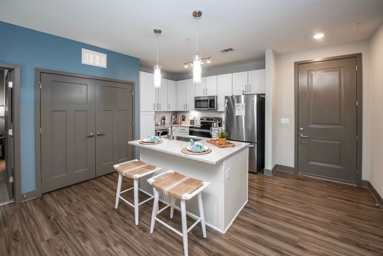 Open-concept kitchen with island, white cabinets, and stainless-steel appliances.