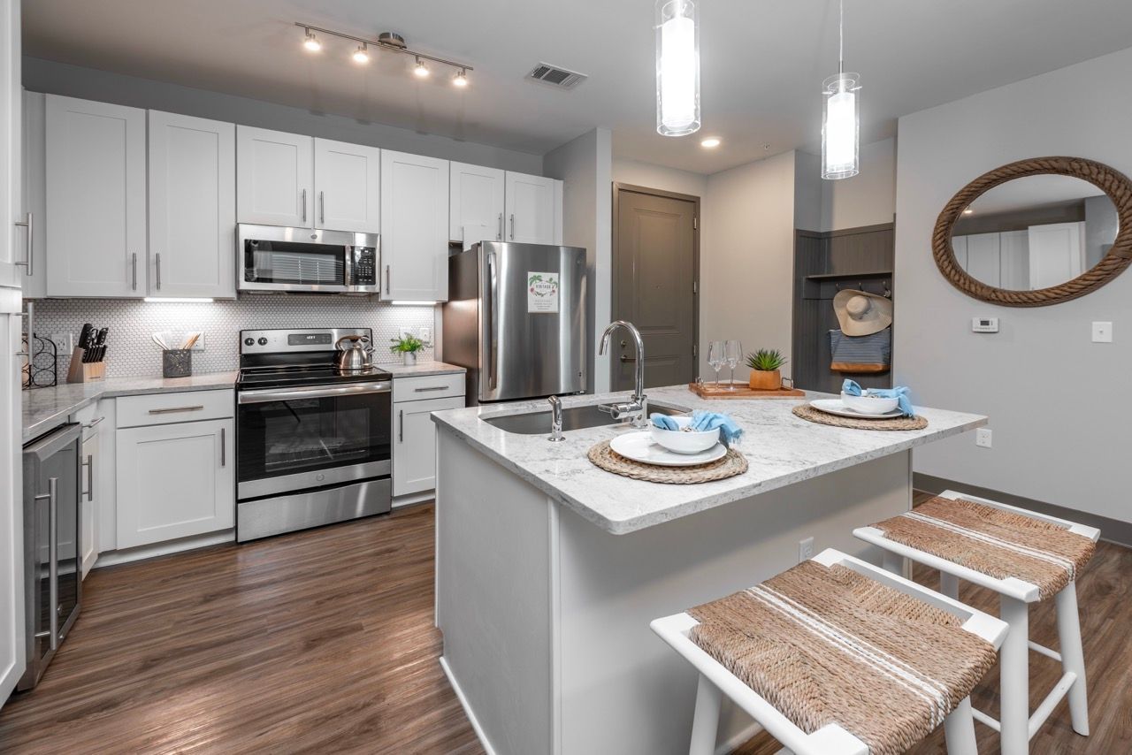 Modern apartment kitchen with white cabinets, stainless steel appliances, and an island.