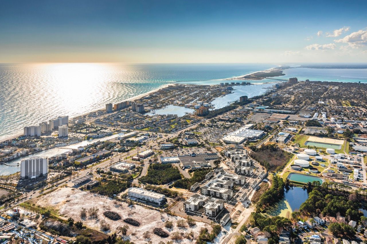 Aerial view of a coastal urban area with buildings, roads, and shoreline.