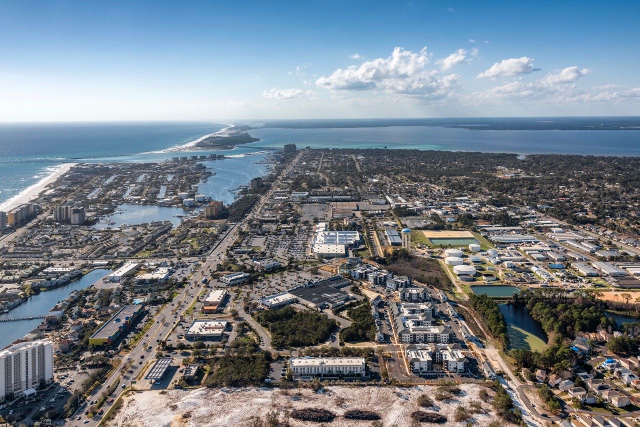 Aerial view of a coastal city with beaches, canals, and dense buildings.