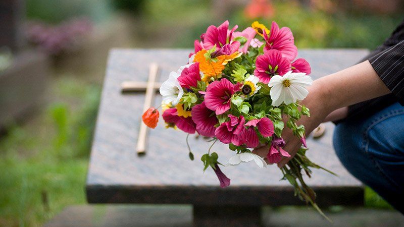 person holding flowers over a grave