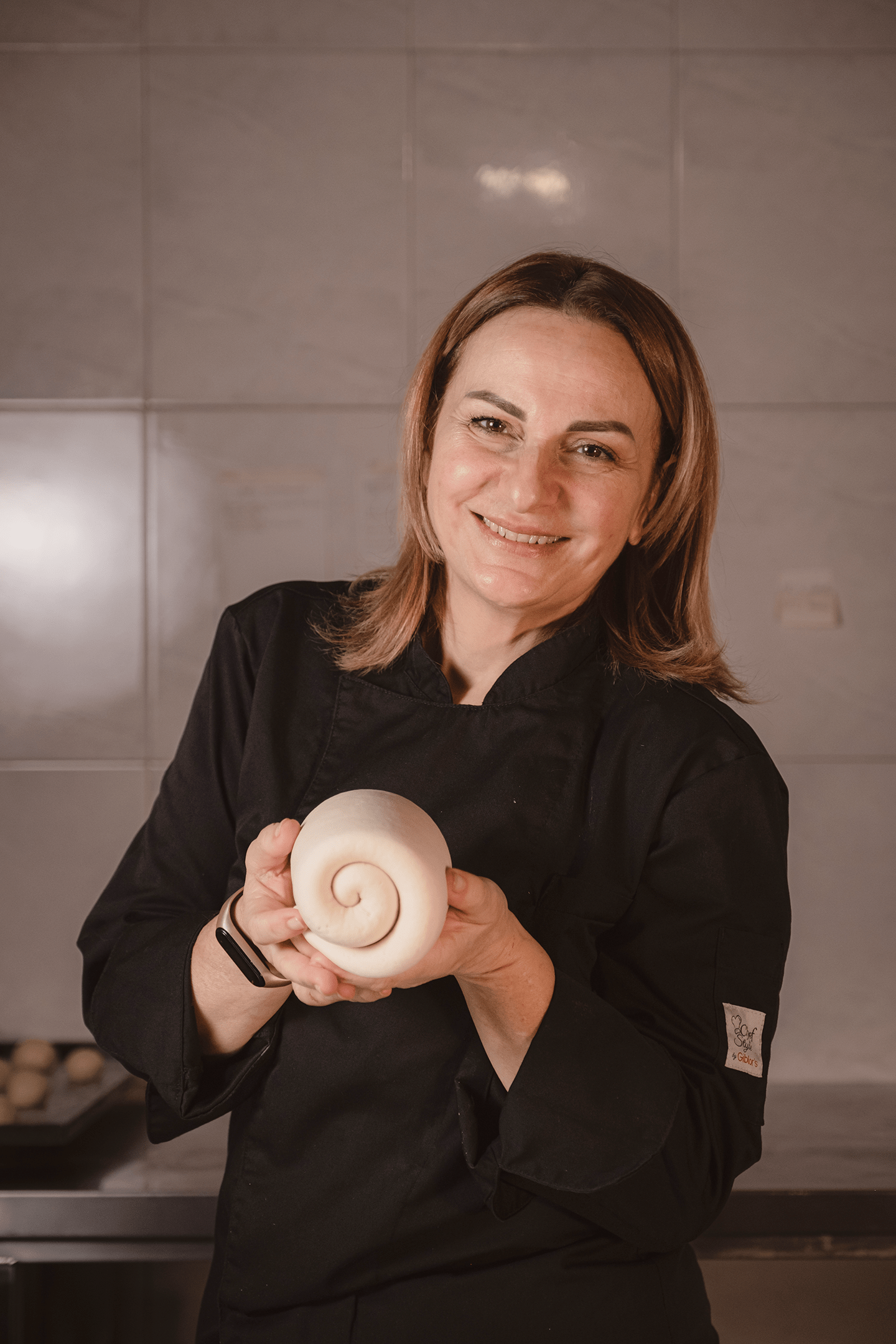 Una donna con una giacca nera tiene un ricciolo tra le mani.