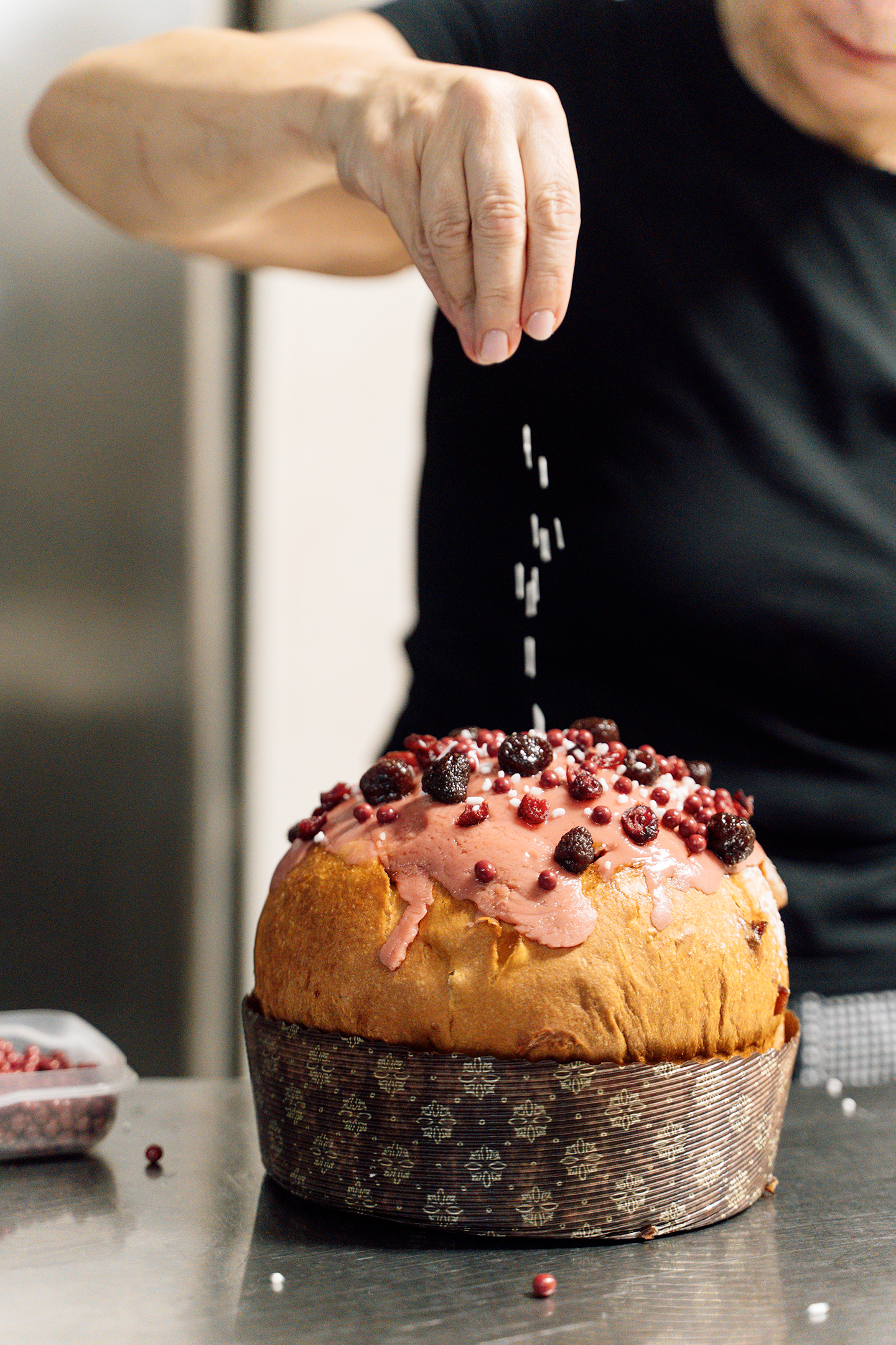 Una persona sta cospargendo di granella una torta su un tavolo.