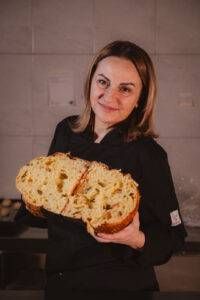 Una donna con una giacca nera tiene un ricciolo tra le mani.