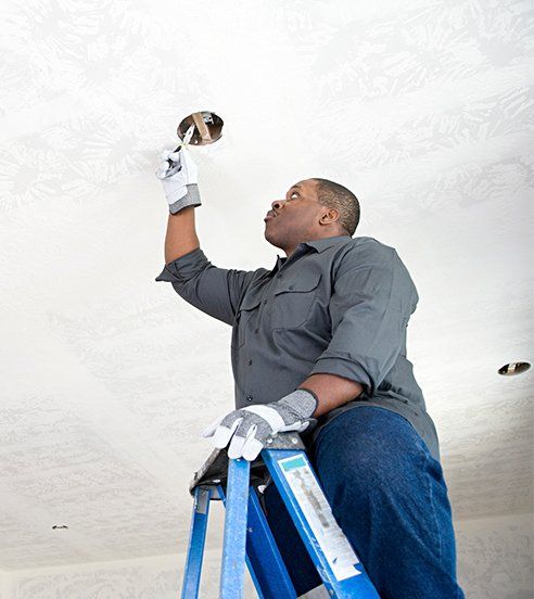 Electrician — Man Fixing The Light Outlet in Raleigh, NC