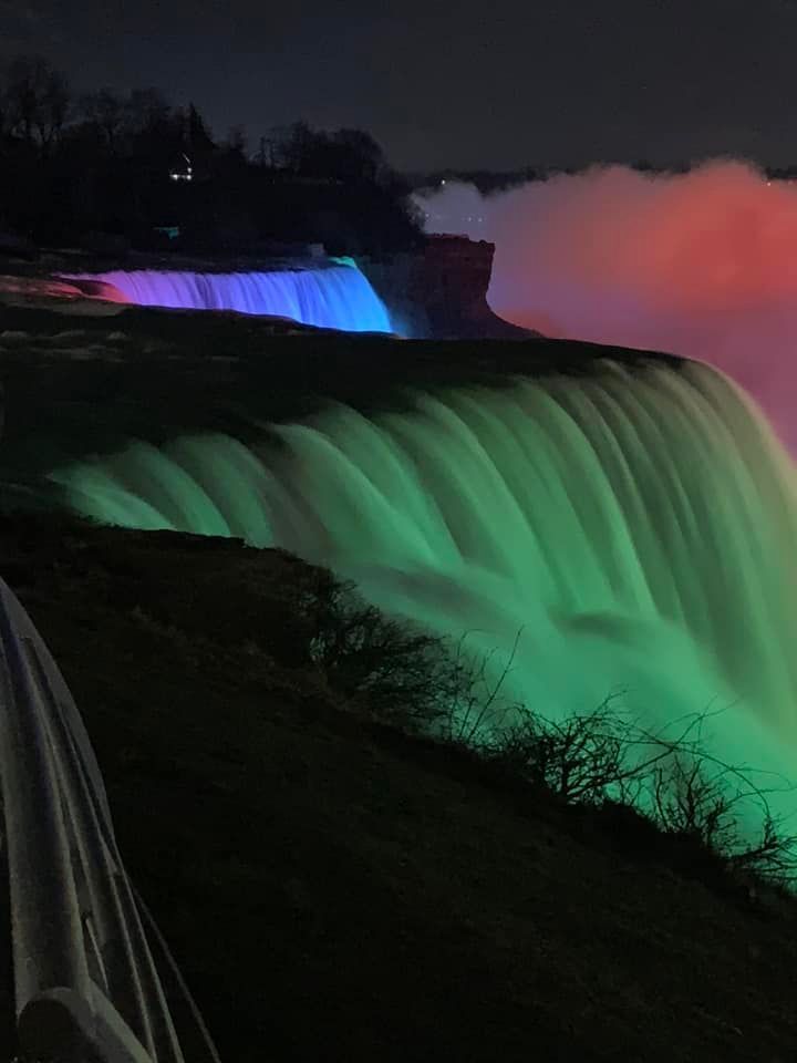 A waterfall is lit up with different colors at night