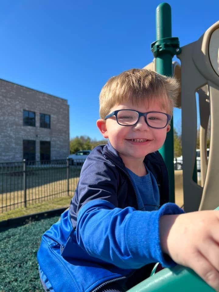 A young boy wearing glasses is playing on a playground.