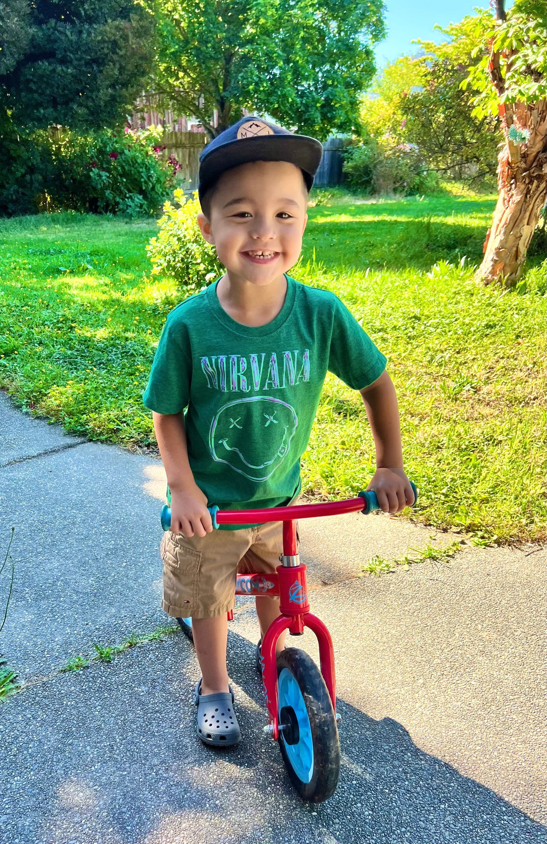 A young boy is riding a balance bike on a sidewalk.
