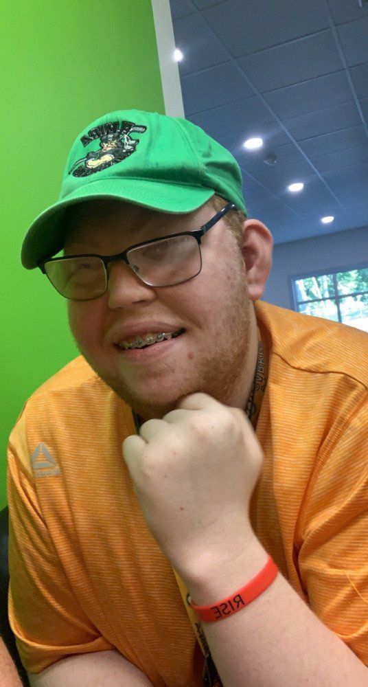 A man wearing a green hat and glasses is smiling.