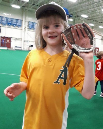 A little girl wearing a yellow jersey with the letter a on it