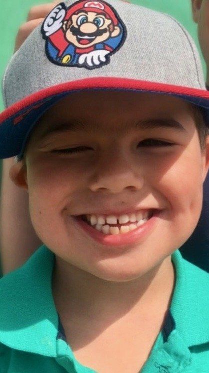 A young boy wearing a hat with mario on it.