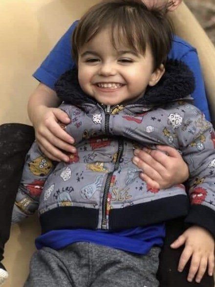 A little boy is being held by a man and smiling.