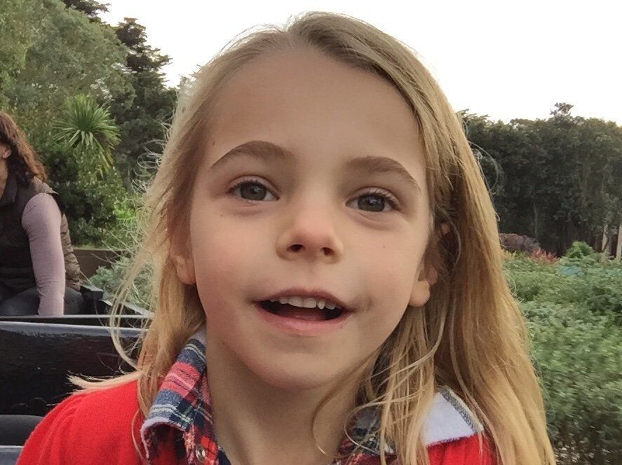 A little girl with long blonde hair is smiling for the camera.