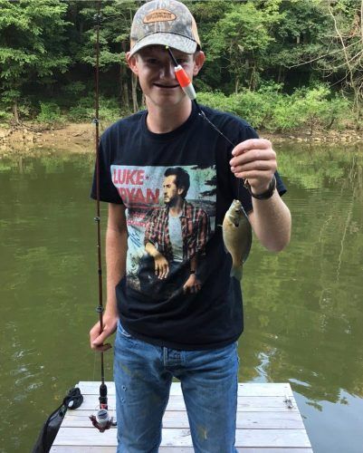 A man is standing on a dock holding a fishing rod and a fish.