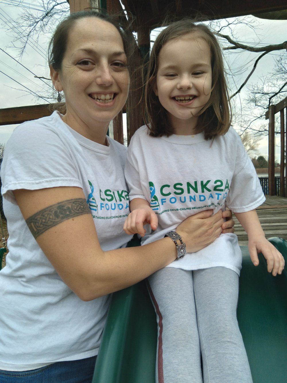 A woman is holding a little girl who is sitting on a slide.